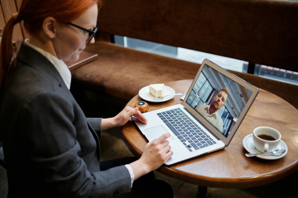 pexels-photo-5917842-5917842 Business woman engaged in a video call meeting in a cozy cafe setting, using a laptop.